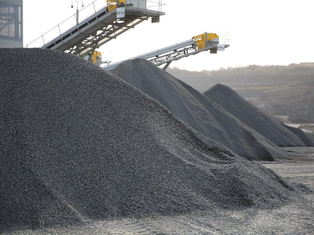 Gravel mounds and conveyor belts in an industrial quarry setting.