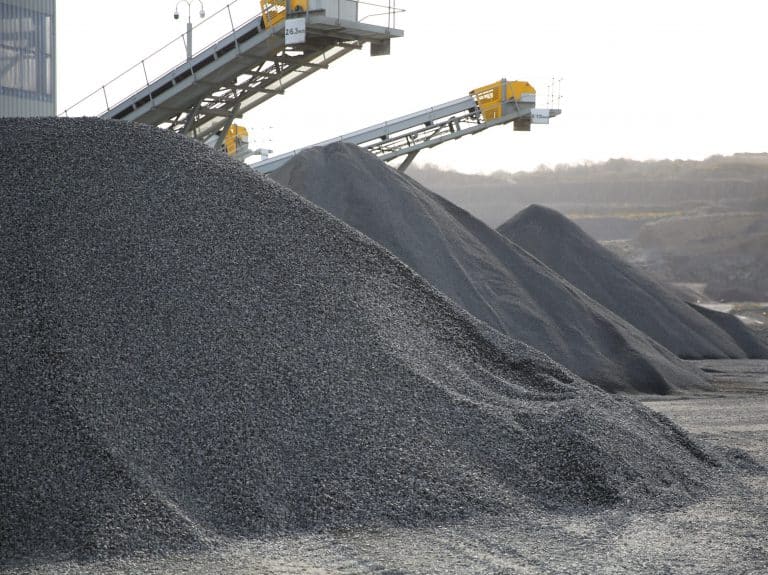 Gravel mounds and conveyor belts in an industrial quarry setting.