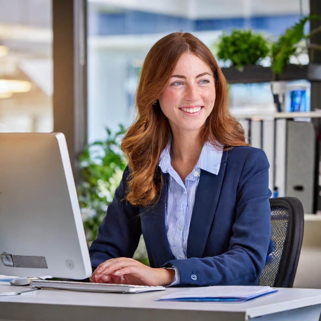 Cheerful administration assistant working at a computer