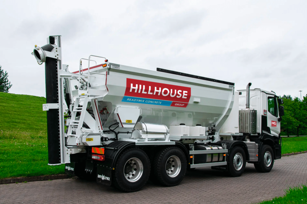 White concrete truck with Hillhouse branding, mixing drum, on paved road with greenery.