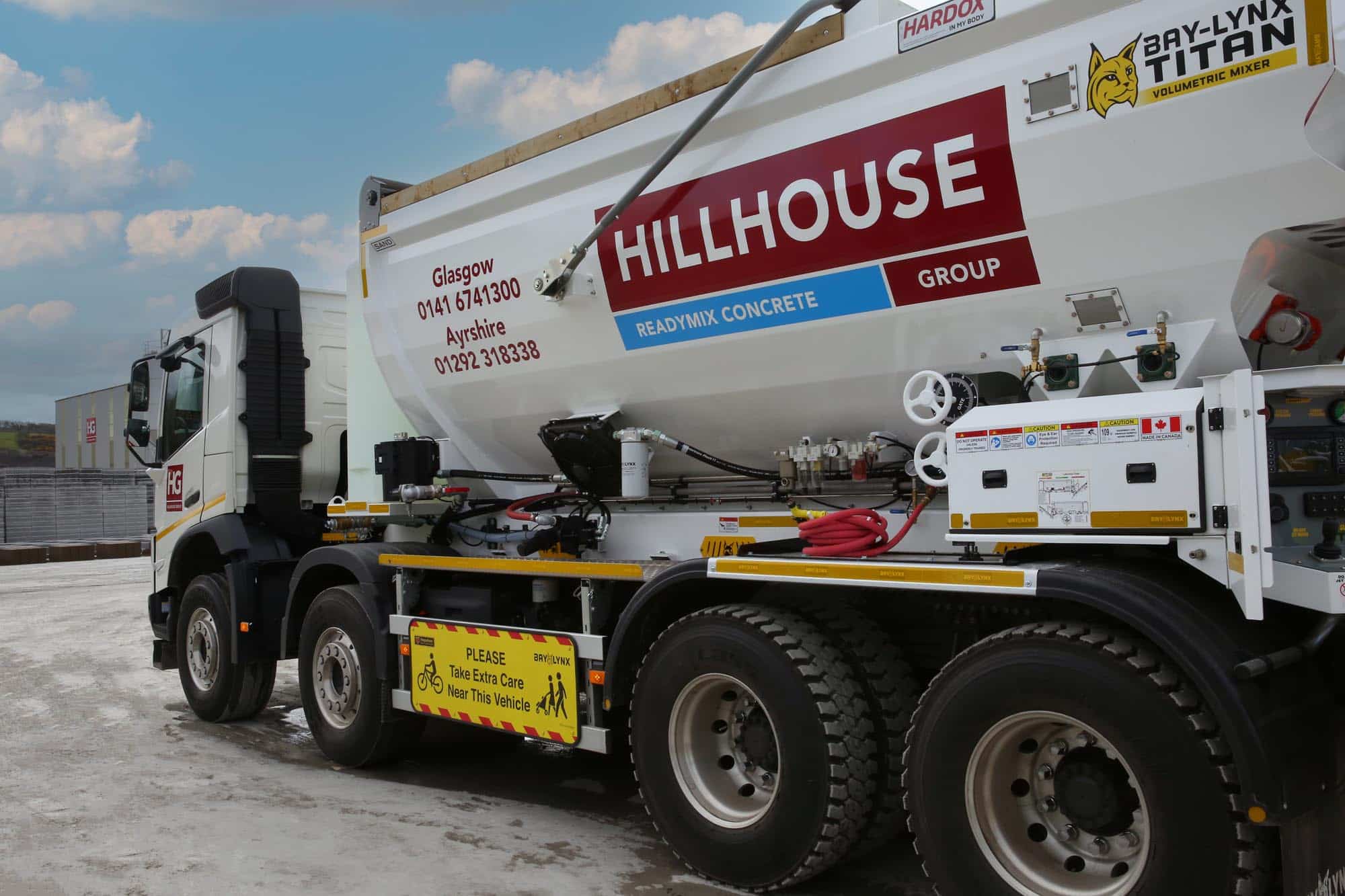 Volumetric mixer truck with construction branding and safety signs, on concrete surface.