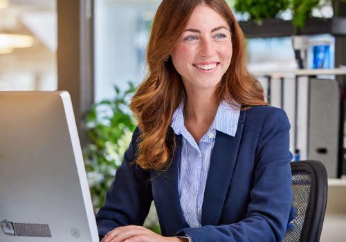 Cheerful administration assistant working at a computer