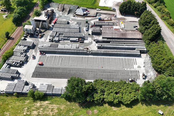 Aerial view of industrial site with concrete blocks and construction materials Aerial view of industrial site with stacked concrete blocks, machinery, buildings, road, and railway.
