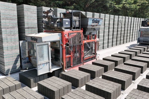 Concrete block manufacturing site with Finlay machines stacking blocks in rows and tall stacks.