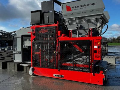 Industrial block-making machinery by McGirr Engineering, grey and red, on concrete with blocks nearby.