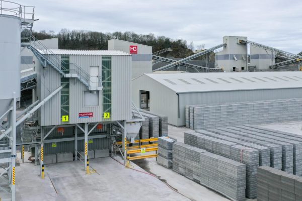 Industrial facility with storage tanks, conveyor belts, concrete blocks, and warehouse.