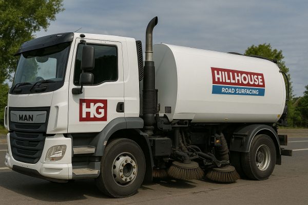 Road sweeper truck with HG and Hillhouse Road Surfacing logos, on a paved outdoor area.