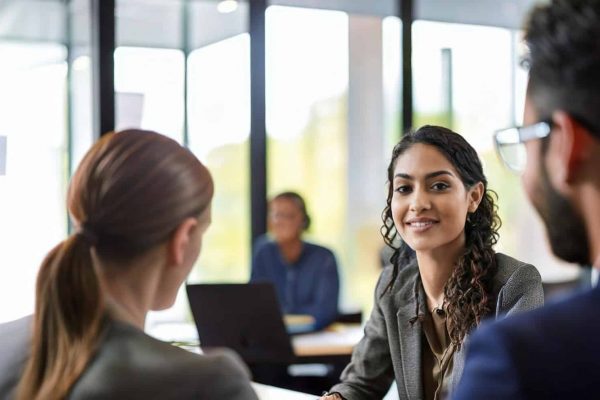 Business meeting with a woman smiling attentively in a modern office setting.